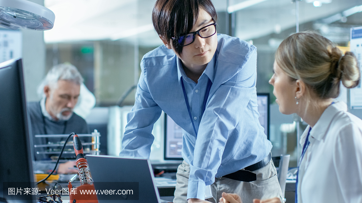 女計算機科學家用綠色屏幕模型連接電路板到她的筆記本電腦。她在先進技術實驗室工作。